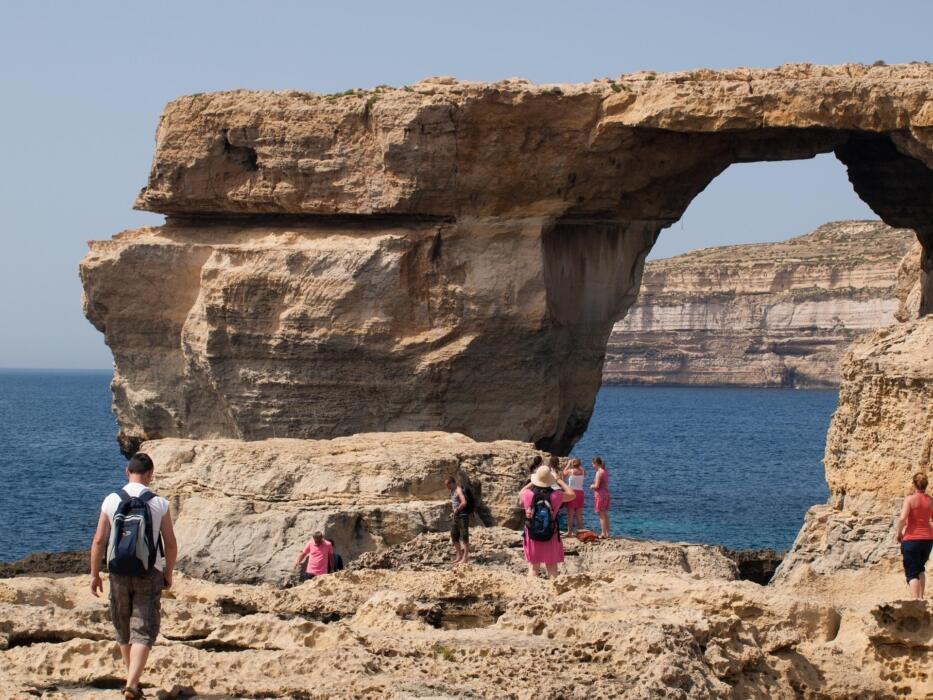 Tourists exploring the Azure Window rock formation on the coast of Gozo, Malta.